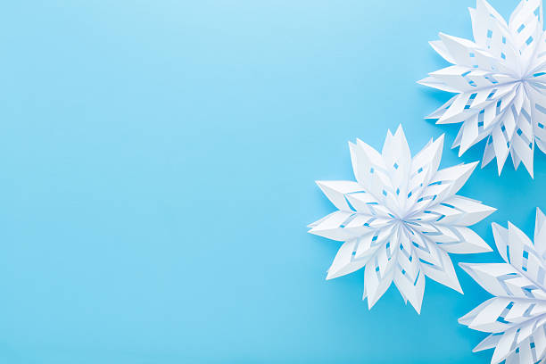istock White snowflake shapes created from paper on light blue table background. Pastel color. Closeup. Handmade decoration elements for winter festive. Empty place for text. Top down view. 2251155754