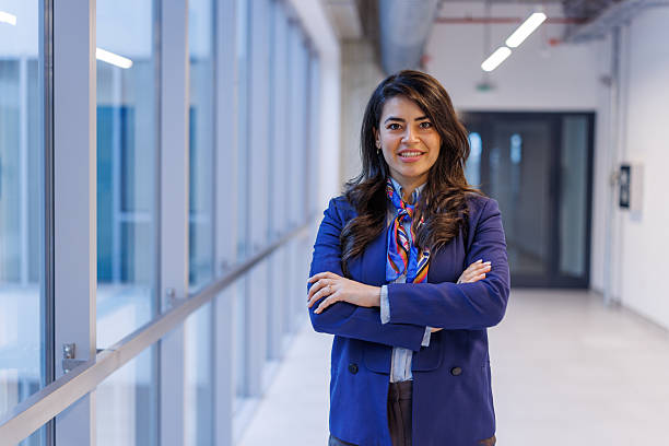 istock Confident businesswoman smiling while standing in modern office hallway 2251156237