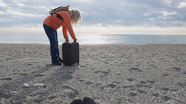 istock Woman with carryon suitcase on beach 2251157587