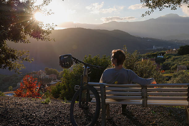 istock Mountain biker sits on bench above hills at sunset 2251157758
