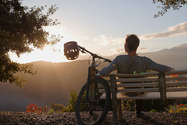 istock Mountain biker sits on bench above hills at sunset 2251157760