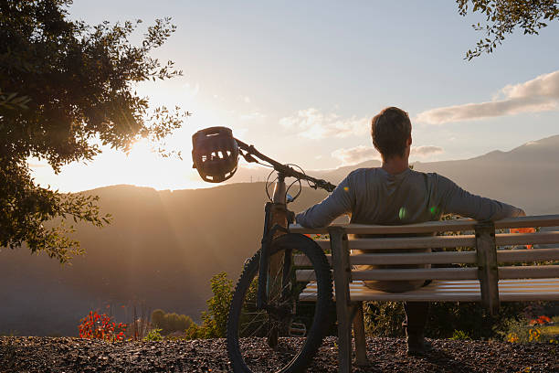istock Mountain biker sits on bench above hills at sunset 2251157763