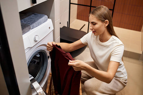 istock Young Woman Loading Laundry into Washing Machine Indoors 2251158108