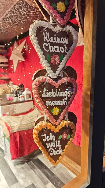 This festive photo captures a set of traditional German gingerbread hearts (Lebkuchenherzen) hanging in a Christmas market stall. Decorated with colorful icing and loving messages in German