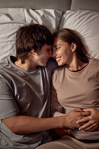 istock Young Couple Lying in Bed Smiling and Embracing Affectionately 2251162312