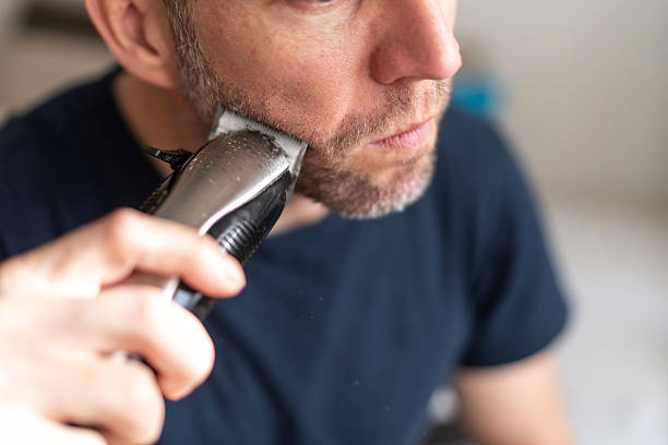 istock Man trimming beard using electric razor at home 2251163497