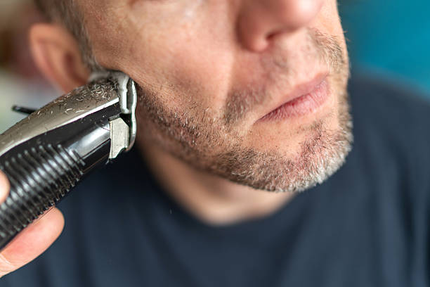 istock Man shaving beard with electric trimmer close up 2251163530