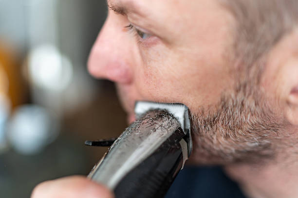 istock Man shaving beard with electric trimmer close-up 2251163548