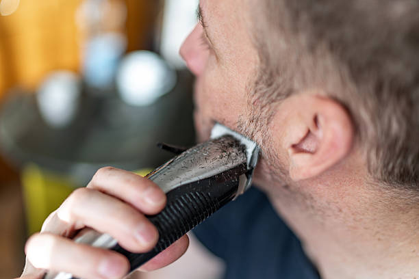 istock Man shaving beard with electric trimmer close-up 2251163614