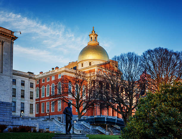 Boston, Massachusetts, USA - December 6, 2025:  The Massachusetts State House, also known as the Massachusetts Statehouse or the New State House, is the state capitol and seat of government for the Commonwealth of Massachusetts, located in the Beacon Hill neighborhood of Boston. A statue of the late U. S. President John F. Kennedy is in the foreground. The building houses the Massachusetts General Court (state legislature) and the offices of the Governor of Massachusetts. The building, designed by architect Charles Bulfinch, was completed in January 1798 and has repeatedly been enlarged since. It is one of the oldest state capitols in current use. It is considered a masterpiece of Federal architecture and among Bulfinch's finest works, and was designated a National Historic Landmark for its architectural significance.