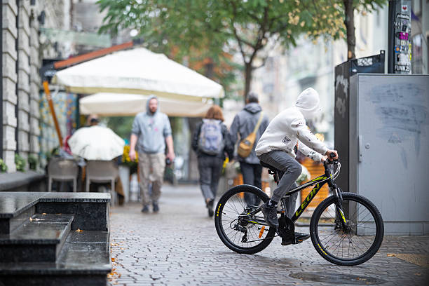 Portrait of young male college student on bicycle on the city street. Caucasian man enjoying on bicycle in the city and looking at camera.