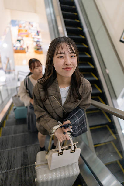 Young female tourists moving up on escalator