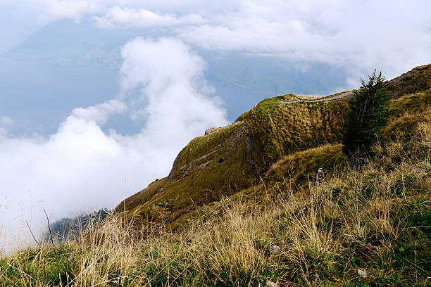 Steep mountain ridge with dry alpine grass, overlooking clouds on Mount Rigi, Switzerland