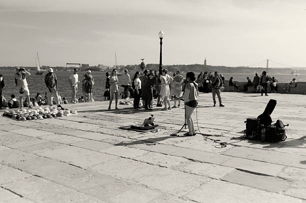 Lisbon, Portugal - May 31, 2025: A street musician plays guitar and sings by the Tagus River in Lisbon downtown.