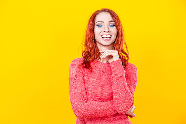istock Fancy Winsome Lady in Coral Knitted Sweater Posing With Hands Folded In Front Looking Aside And Smiling Yeah Win Lottery WIth Tranquil Expression Isolated On Yellow Background. 2251180386