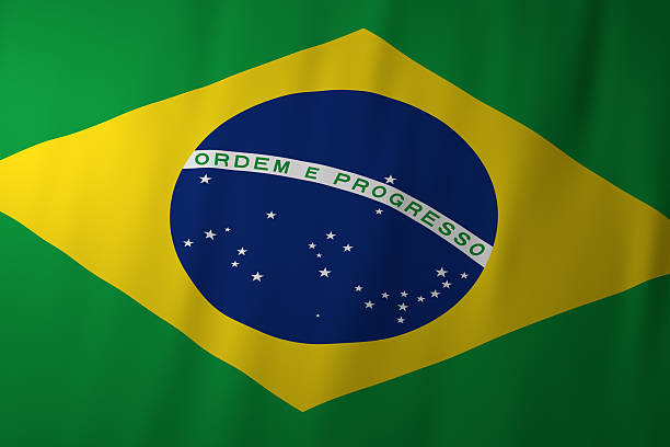 The image shows the national flag of Brazil, featuring a green field with a large yellow diamond in the center. Inside the diamond is a blue globe with white stars and a curved white banner displaying the motto “Ordem e Progresso,” symbolizing order, progress, and the nation’s unity.