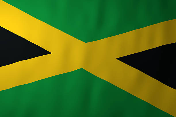 The image shows the national flag of Jamaica, featuring its distinctive gold diagonal cross dividing the green and black fields. The gently waving fabric enhances the bold colors and dynamic geometric design.