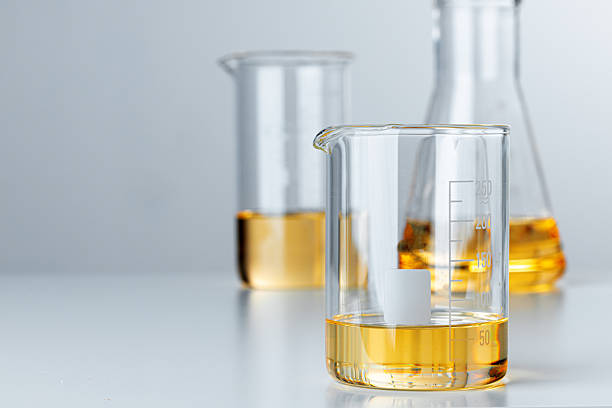 istock Laboratory glassware with yellow oily liquid on grey background 2251182412