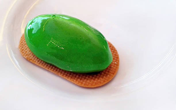 Glossy green mirror glaze mousse cake served on a textured biscuit base.