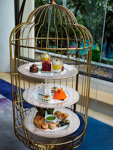Luxurious gold birdcage afternoon tea stand featuring three tiers of savory and sweet gourmet treats