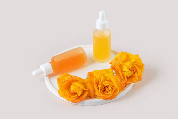 istock two dropper bottle  on a white tray and yellow rose flowers on a light background. Presentation of skin care products. 2251187295