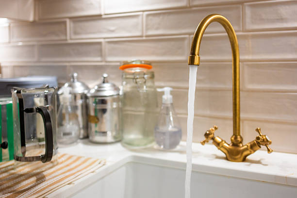 istock Water running from brass tap at ceramic kitchen sink 2251190096