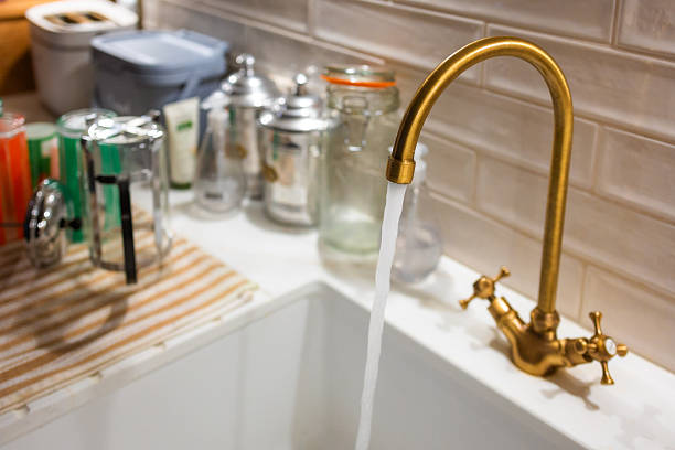 Water flowing out of a brass tap into a ceramic sink in the kitchen.