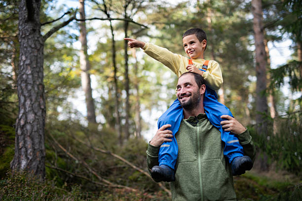 istock Father carrying son piggyback pointing during forest hike. 2251198285