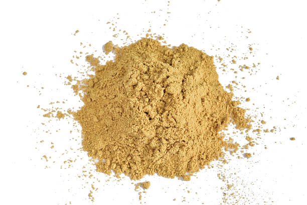 A pile of yellow ground mustard powder on a white background.