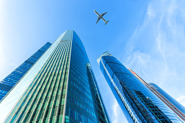 istock Modern glass skyscrapers on a clear day and passenger plane flies over 2251205800