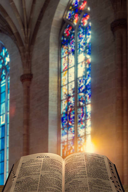 istock Open Bible in sunlight near stained glass window 2251209574