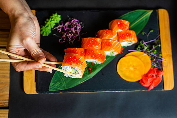istock Hand Holding Chopsticks with Fresh Salmon Maki 2251212507