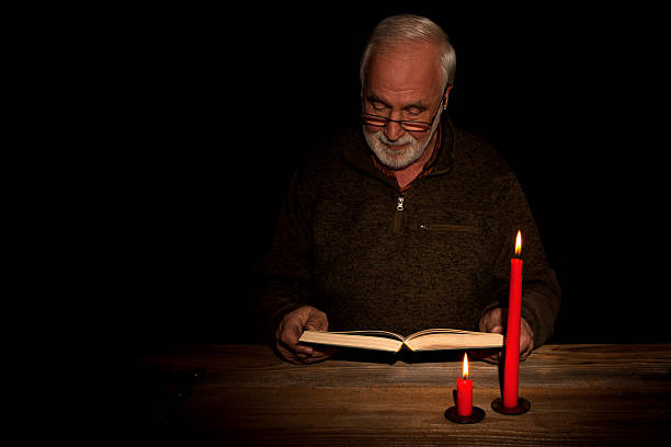 Senior man closing old dusty book against black background