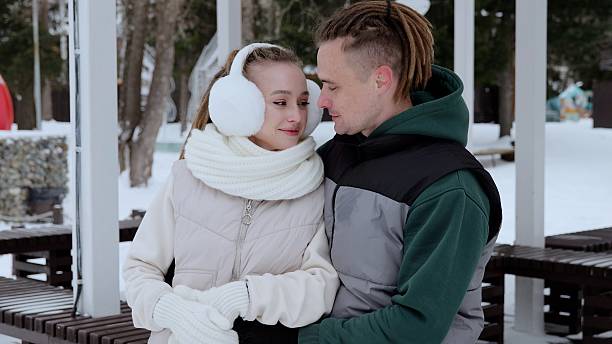 Romantic couple hugging closely, sharing intimate moment while snowflakes softly falling around passionate embrace in winter landscape