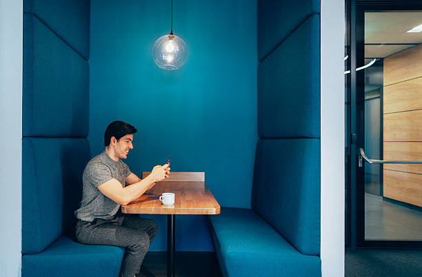 istock Man relaxing in a coworking booth with a smartphone. 2251220717