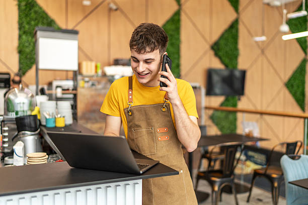 istock Barista multitasking, talking on phone, using laptop in coffee shop 2251220745