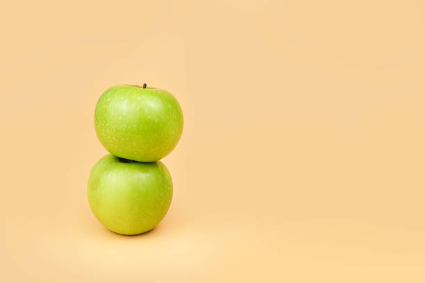 istock Two green apples on a pastel background with clean copy space, representing healthy eating, nutrition choices, minimal lifestyle, and fresh organic food concepts. 2251226818