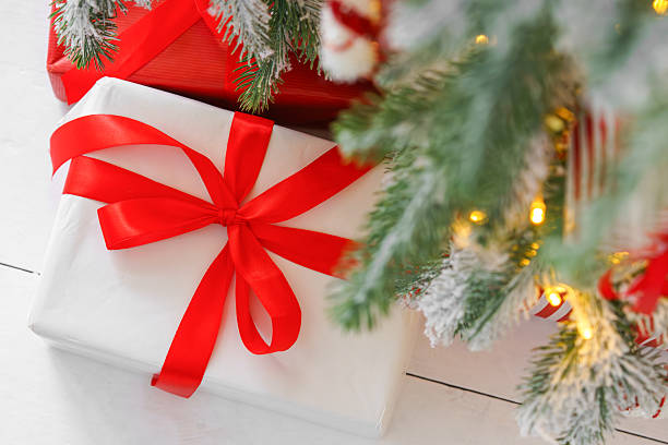 istock White wrapped gift box, present under festive Christmas tree with lights and holiday decorations 2251229510
