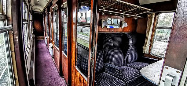istock Empty interior view of long narrow corridor with old fashioned train carriage compartments. Deserted railway car hallway. Railways passenger cabin seats, tables and windows. Commuting travel in vacant seating cabins.. Unoccupied disused transportation. 2251231139