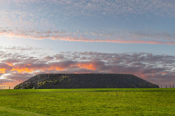 Listoghil megalithic tomb at Carrowmore ancient ritual landscape on west of Sligo, Ireland built in 4th millennium BC during Neolithic period (New Stone Age) with clouds lit orange up during sunset