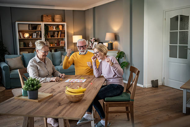 istock Senior friends cheering playing board game at home 2251231244