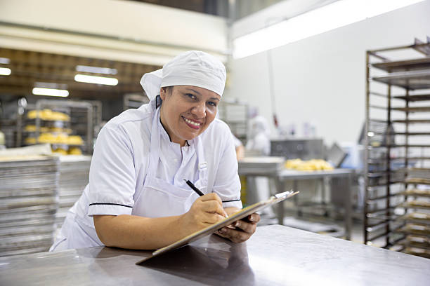 istock Employee working at a bakery and writing on a clipboard 2251231443
