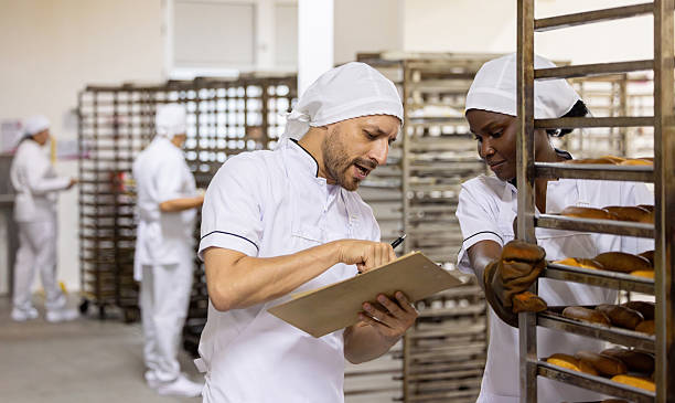 istock Supervisor talking to an employee transporting bread at the bakery 2251231518