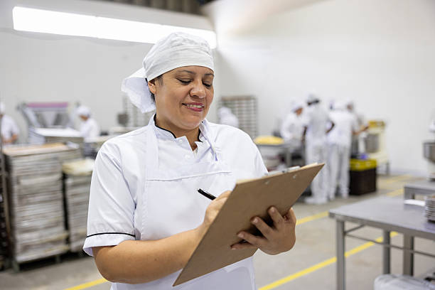 istock Happy manager writing on a clipboard while working at an industrial bakery 2251231606