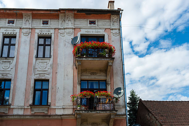 Tarnow, Poland – July 12, 2025: A historic townhouse features ornamental plasterwork and balconies overflowing with red flowers, adding color and elegance to the old district.