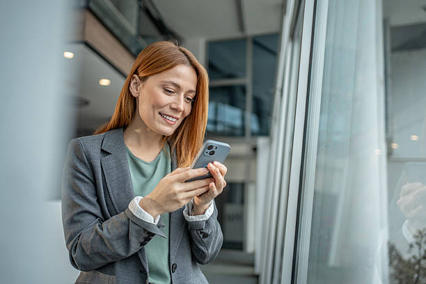 istock Professional businesswoman smiling while sending message on smartphone 2251234506