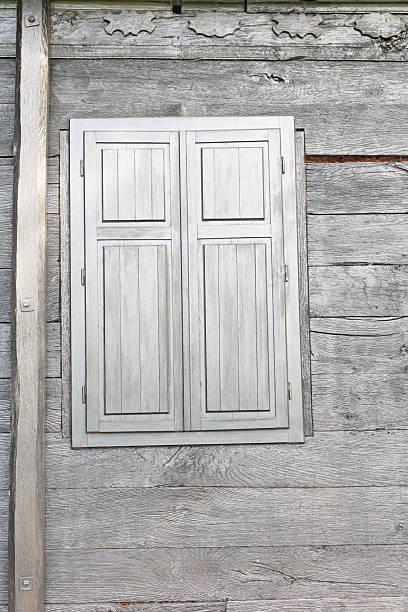 Rustic wooden wall showcasing a vibrant texture and closed shutters, highlighting charming simplicity and elegance of wooden craftsmanship.