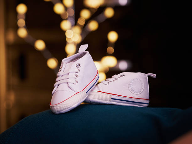 istock Single white baby shoe with warm lights in background 2251239649