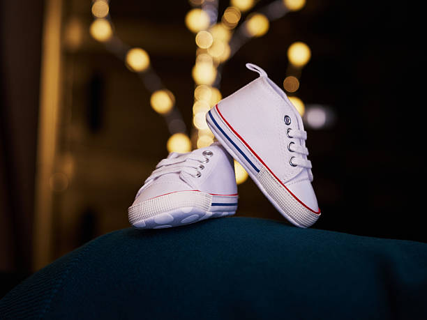 Pair of rainbow-soled baby shoes photographed on fabric with warm lights behind