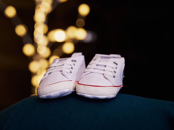 istock Single white baby shoe with warm lights in background 2251239673